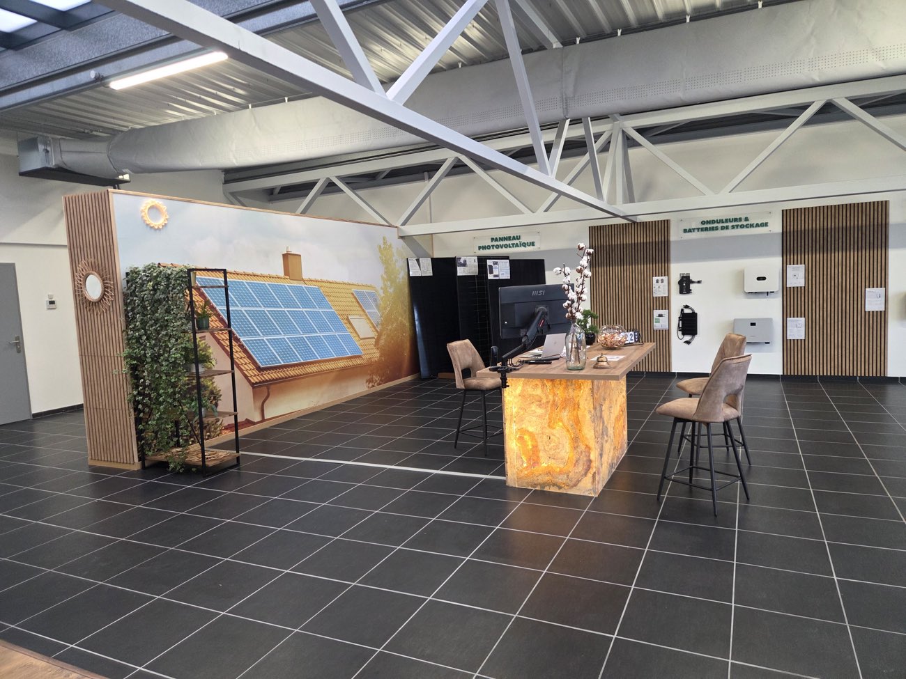 Le mur photovoltaïque du showroom, devant la fresque peinte d'une maison équipée de panneaux.