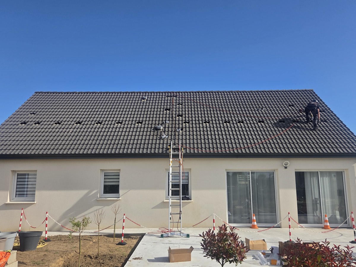 Toiture en cours de préparation, tuiles déposées aux points de fixation, échelle en place.
